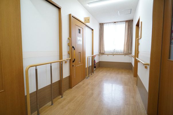 施設の写真 床に段差が極力なく、壁に手すりがあるバリアフリー化された廊下