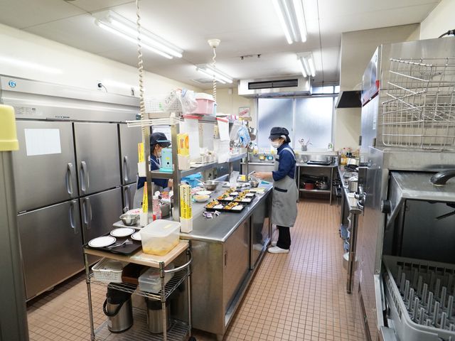 忙しく働くキッチンスタッフ 厨房 衛生的に保たれたキッチンで、スタッフが丁寧に食事の準備をしています。栄養バランスを考えた手作りの食事を、ここで作り上げています。