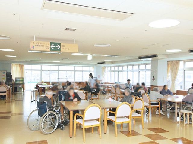くつろげる広々とした空間 リビング 自然光が差し込む広々としたスペースで、多くの人がリラックスしています。車椅子の方も快適に過ごせます。