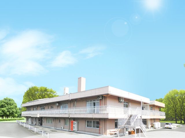 緑に囲まれた建物 外観 自然に囲まれた施設で、心地よい環境が広がっています。青空の下で、清々しい日常を感じられます。
