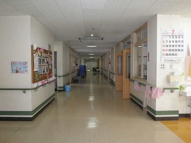 長い廊下が見える空間 廊下 幅広い廊下は、車椅子でも移動しやすく安全です。掲示物が並ぶ壁側で、日常の様子が感じられます。