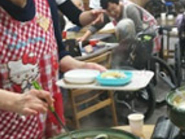 食事を配る様子の部屋 食堂 暖かい食事が配られる場面で、和やかな雰囲気があります。利用者同士の交流も期待できそうです。
