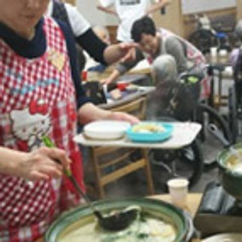食事を配る様子の部屋 食堂 暖かい食事が配られる場面で、和やかな雰囲気があります。利用者同士の交流も期待できそうです。