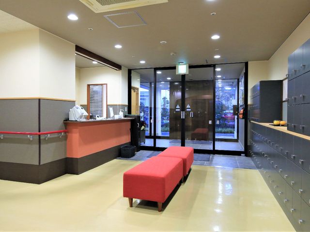 受付とロッカーのあるエントランス 玄関 ゆったりとしたスペースの受付エリアがあり、来訪者の第一印象を安心感でお迎えします。明るく整えられたロッカーエリアもあります。