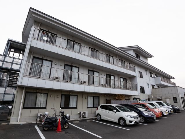 白い建物の外観 外観 清潔感のある白い外壁が目を引く建物で、快適な職場環境を提供しています。車両や自転車も停められる広々とした駐車場があります。