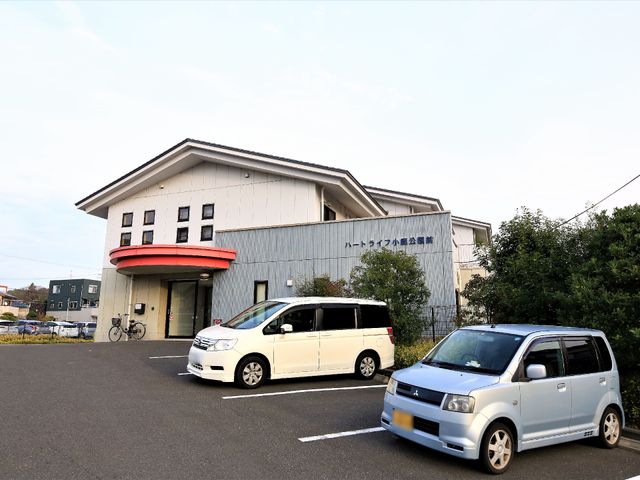 白と赤の建物エントランス 外観 ゆとりのある駐車スペースが確保されており、日々の通勤に便利な環境が整っています。また、明るい色合いの外観は周囲にも馴染んでいます。