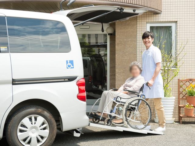 車椅子利用者の介助 外観 介護スタッフが丁寧に車椅子をサポートし、安全に施設の送迎車を利用できる環境です。