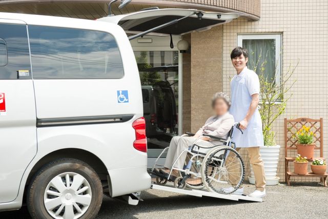 車椅子利用者の介助 外観 介護スタッフが丁寧に車椅子をサポートし、安全に施設の送迎車を利用できる環境です。