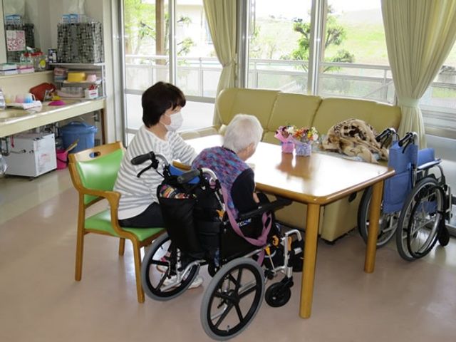 広々としたリビング ラウンジ 自然光がたっぷり入るラウンジで、車椅子を利用する方同士がリラックスした時間を過ごしています。