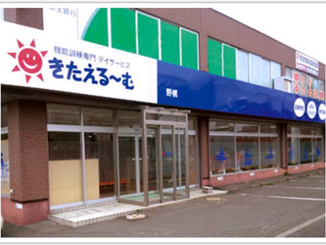 青い看板の建物外観 看板 緑と青の明るい配色が特徴的な建物です。出入りしやすい入り口が備わっています。