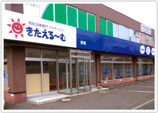 青い看板の建物外観 看板 緑と青の明るい配色が特徴的な建物です。出入りしやすい入り口が備わっています。