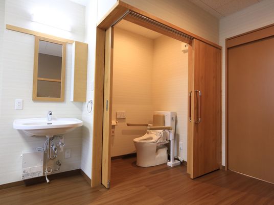 施設の写真 居室のトイレは、ドアのすぐ近くにはある。トイレのドアが2方向に開くことができるため、道が広く出入りしやすい。