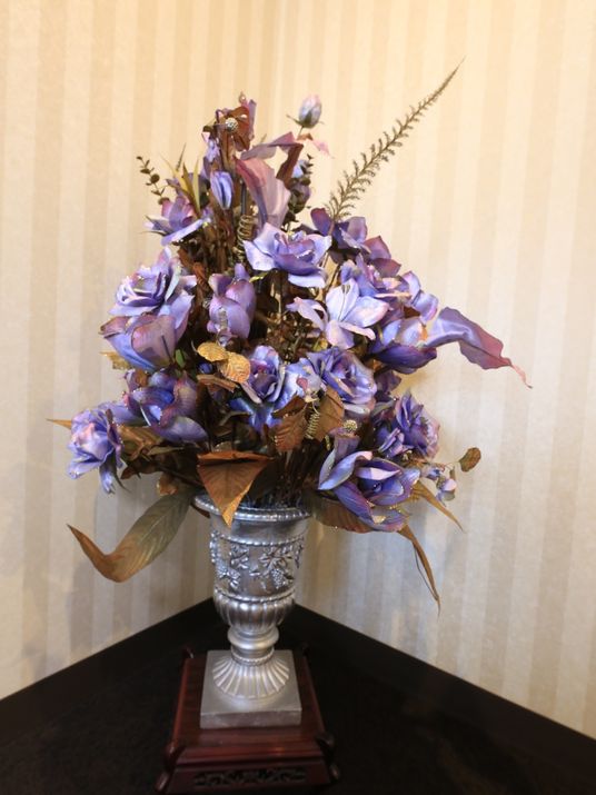 施設の写真 部屋の隅に、銀色の大きな花瓶が置いてあり、青色の綺麗な花の造花が飾られている。これがあることで、部屋に高級感が生まれている。