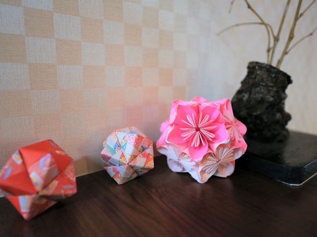 折り紙の花と植木 掲示物 居室に飾られた手作りの折り紙と素朴な植木が、ぬくもりある雰囲気をもたらしています。美しい手仕事が暮らしに彩りを添えています。