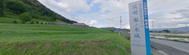 緑に囲まれた案内看板が立つ道