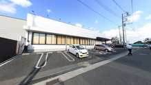 明るい日差しの施設外観と駐車場